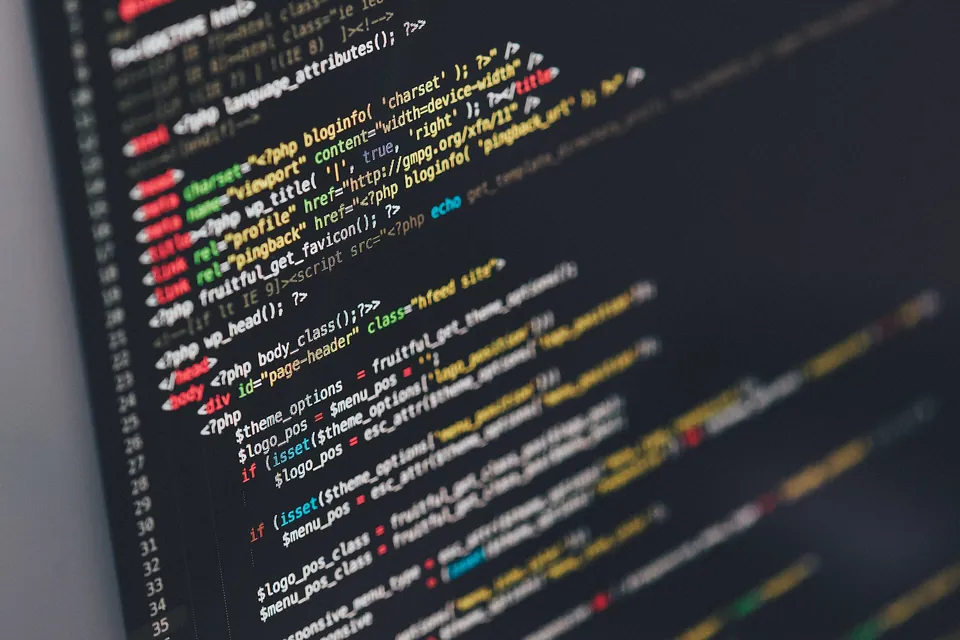 Close-up of a monitor showing lines of colour-highlighted source code